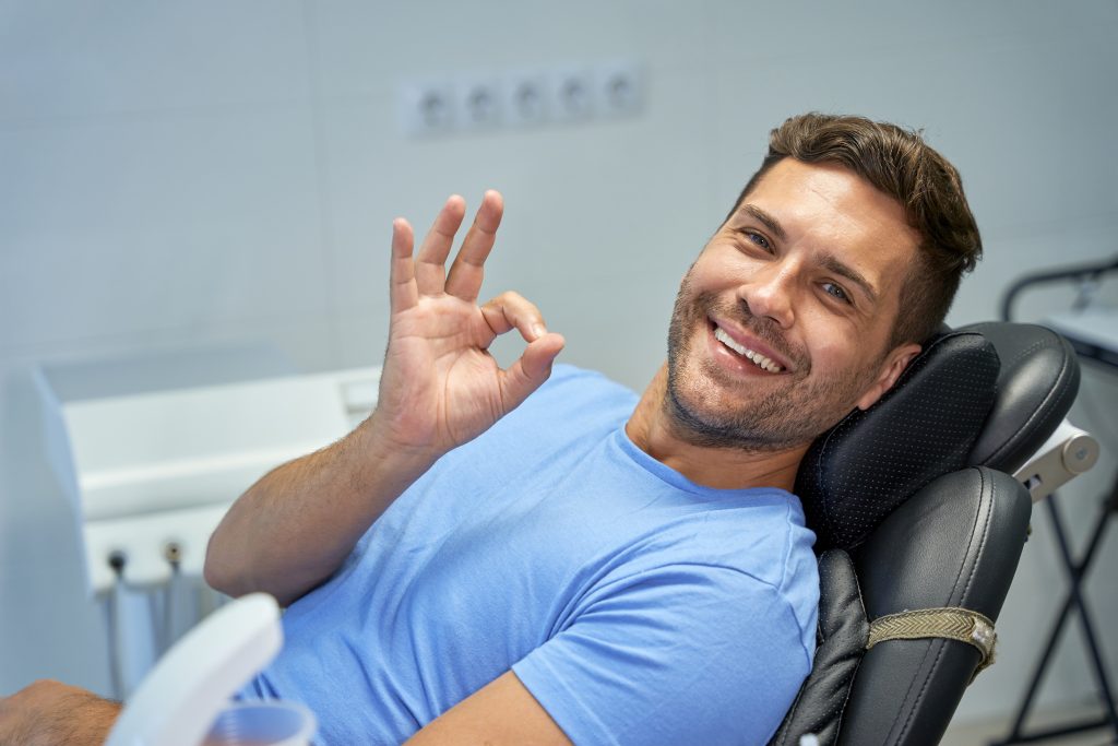 joyeux homme brune souriant au bureau du dentiste