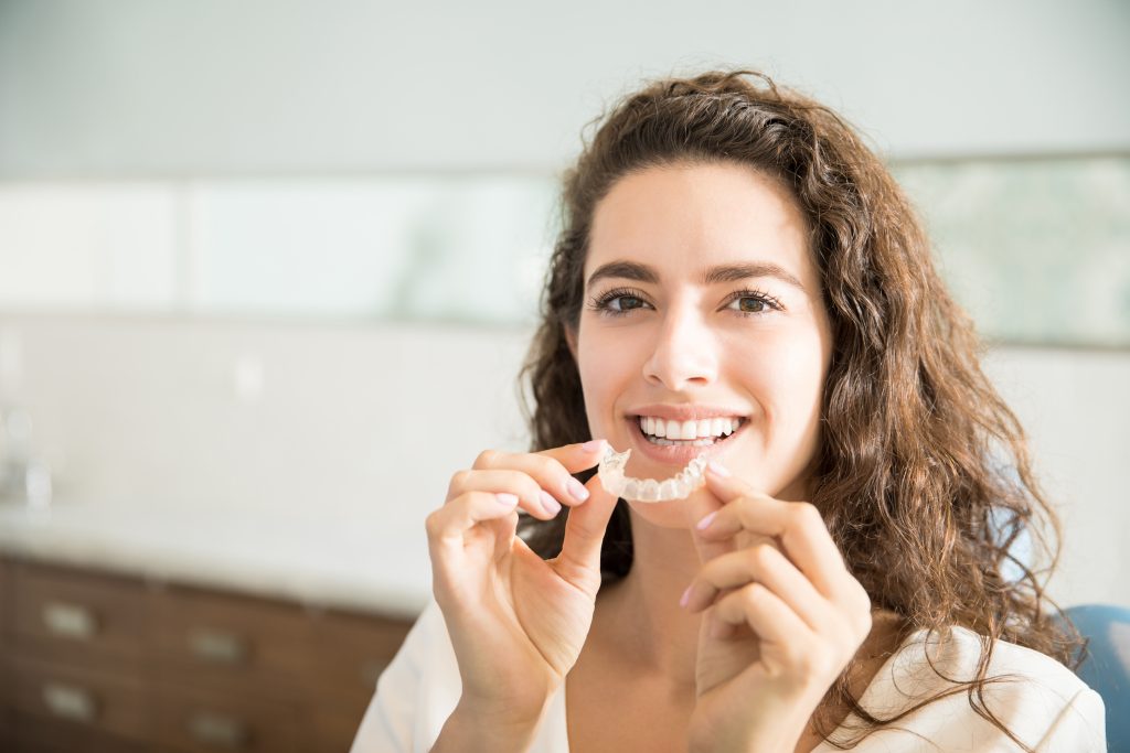 portrait d un beau patient tenant des dispositifs de retenue orthodontiques dans une clinique dentaire